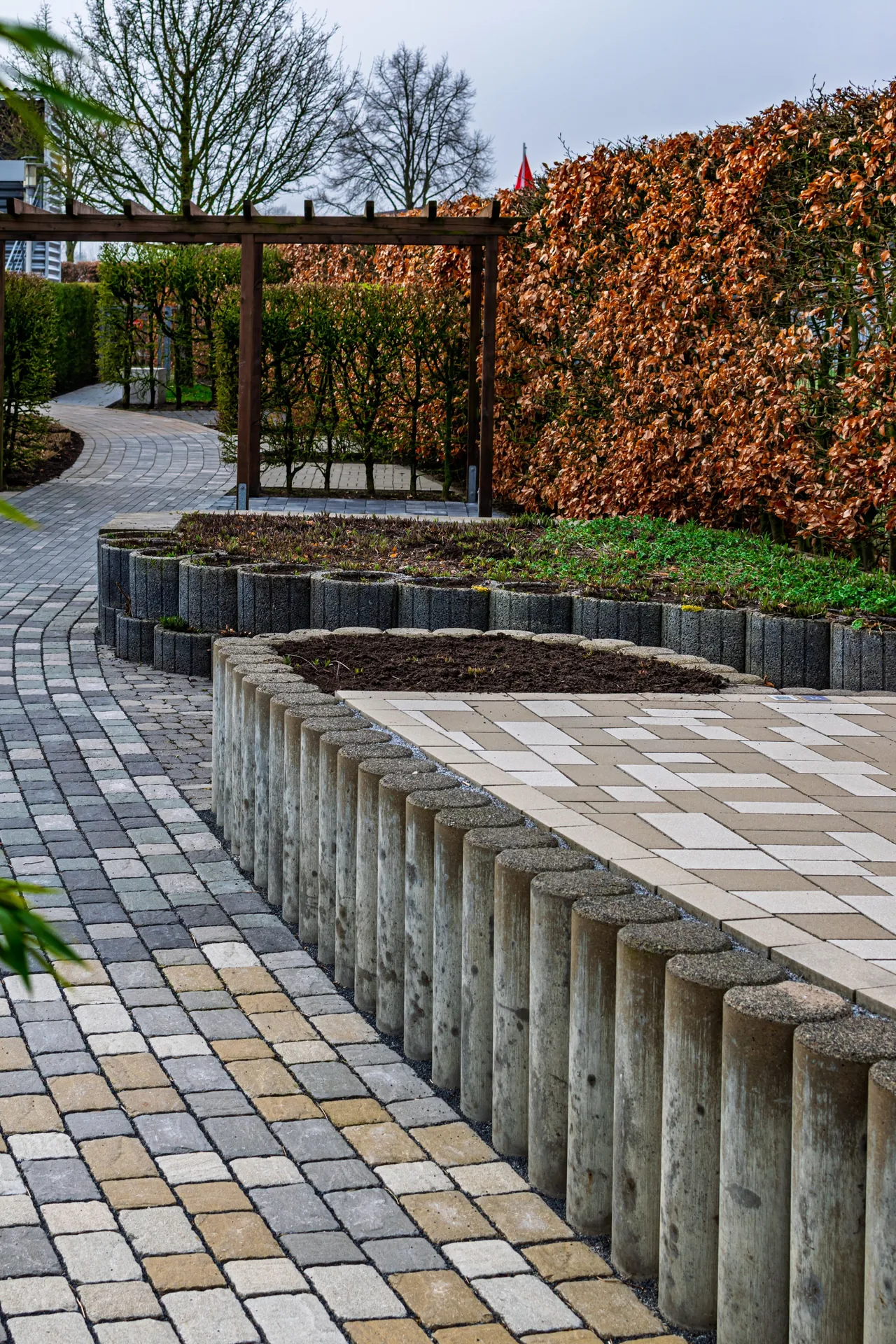 Gepflasterter Gartenweg mit Steinbeeten und Hecken